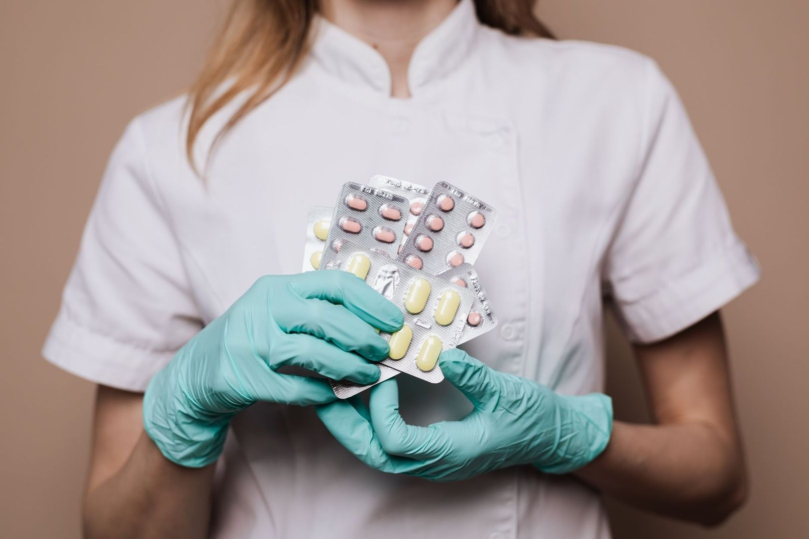 Vårdpersonal i handskar håller flera blisterförpackningar med tabletter